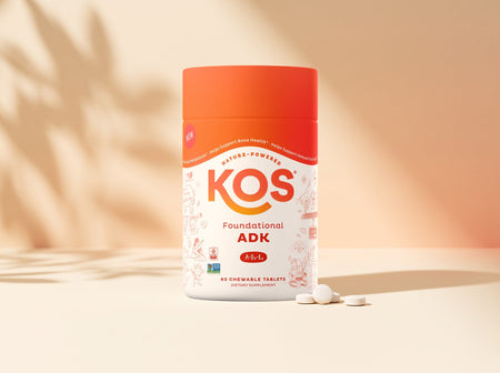 KOS Foundational ADK chewable tablets jar with a few tablets on a warm sunlit backdrop
